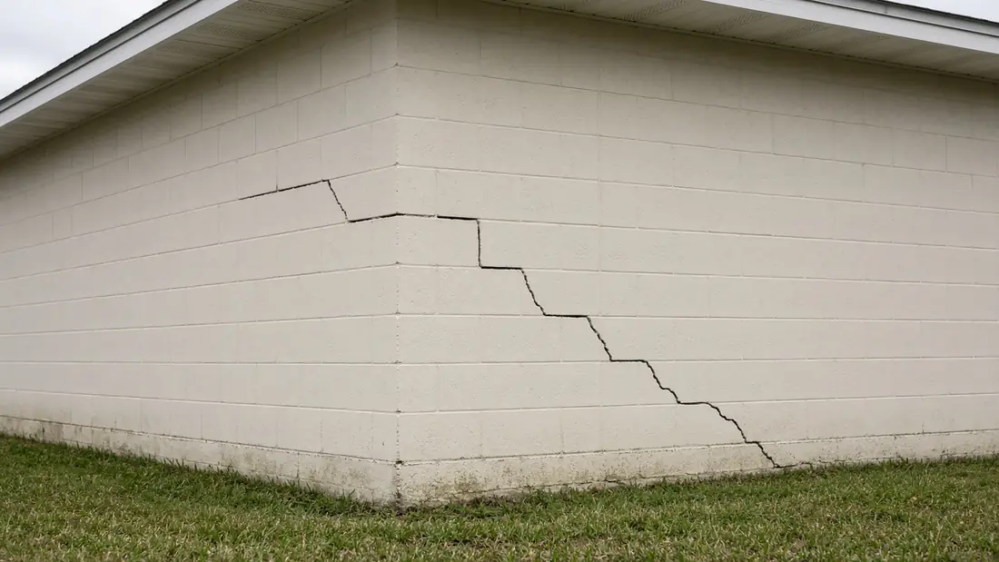 Stair-step crack following the mortar joints of a painted concrete block wall